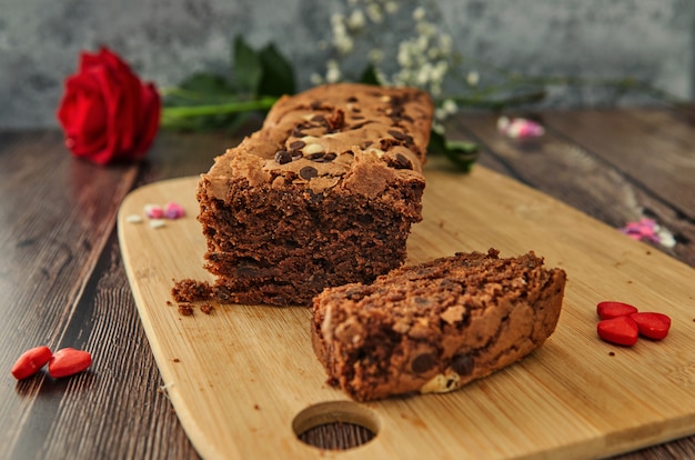 Una torta en una tabla de madera con corazones y una rosa.