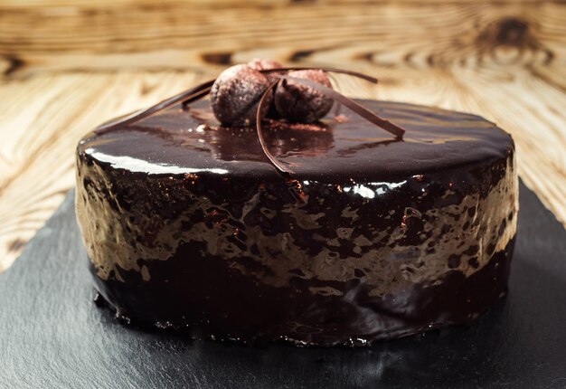 Foto torta vegana de chocolate oscuro con dulces sobre fondo de madera concepto de feliz cumpleaños