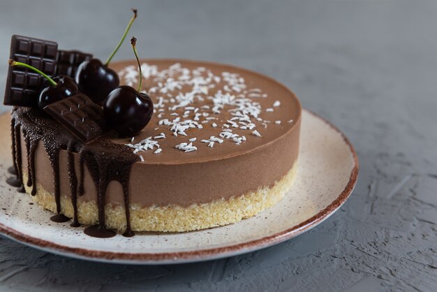 Torta vegana cruda con chocolate y cerezas sobre un fondo gris