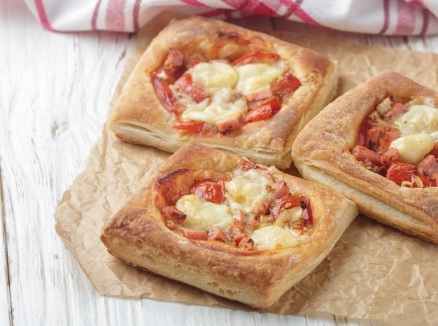 Tortas abertas de massa folhada com tomate, mussarela, cebola e manjericão. Mini pizza. Foco seletivo