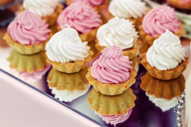 Tortas en la boda blanca y rosa en una bandeja espejada