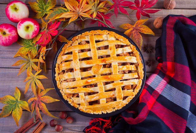 Tortas de maçã na mesa de madeira com folhas de outono e manta