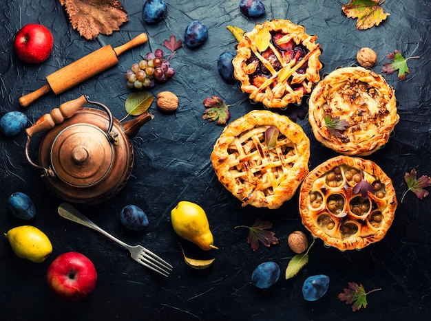 Tortas de outono com pêra, maçã, uvas e ameixa. Doce sobremesa de outono na mesa. Vista superior