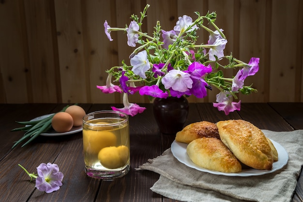 Foto tortas e um buquê de petúnias em uma mesa de madeira.