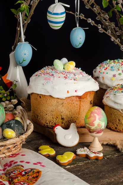 Tortas y huevos de Pascua en una mesa festiva de Pascua con sauce y una figura de un conejo en un fondo oscuro