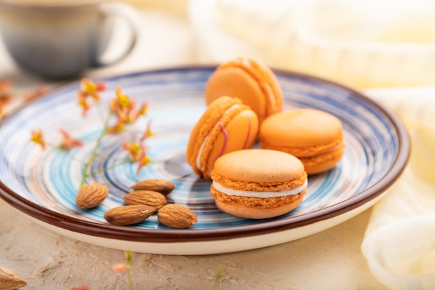 Tortas de macarons de naranja o macarrones con taza de café sobre un fondo blanco