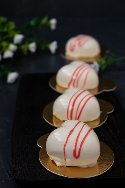 Tortas de mousse caseras Corazones con glaseado de espejo blanco sobre un fondo oscuro