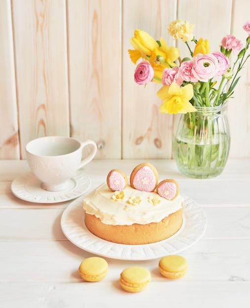 Tortas de Pascua en la mesa, macarrones, huevos y ramo de flores en vaseaster