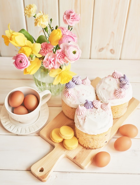 Tortas de Pascua en la mesa, macarrones, huevos y ramo de flores en vaseaster