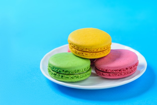 Tortas de taza blanca con macarrones de colores.