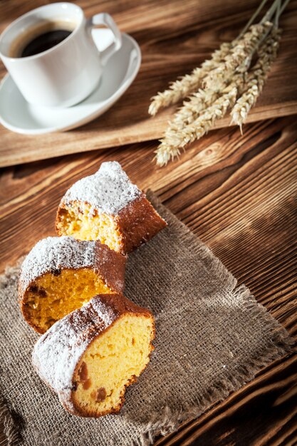 Torte auf Bettzeug mit der Tasse Kaffee auf einem Hintergrund einen Holztisch