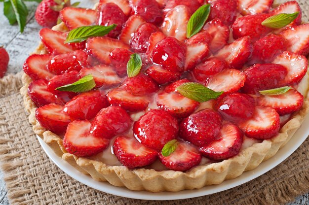 Torte mit Erdbeeren und Schlagsahne, dekoriert mit Minzblättern