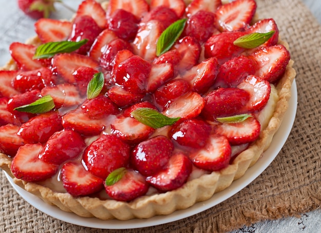 Torte mit Erdbeeren und Schlagsahne, geschmückt mit Minzblättern