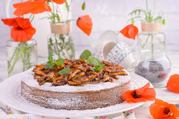 Torte mit Mohn auf einem weißen Hintergrund. Hausgemachtes Gebäck und rote Blumen