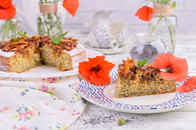 Torte mit mohn auf einem weißen hintergrund. hausgemachtes gebäck und rote blumen