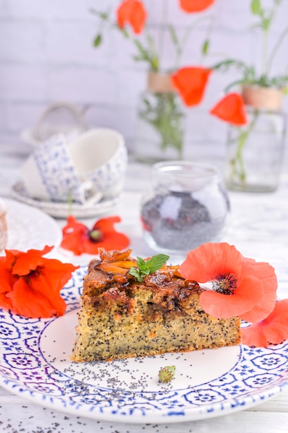 Torte mit Mohn auf einem weißen Hintergrund. Hausgemachtes Gebäck und rote Blumen