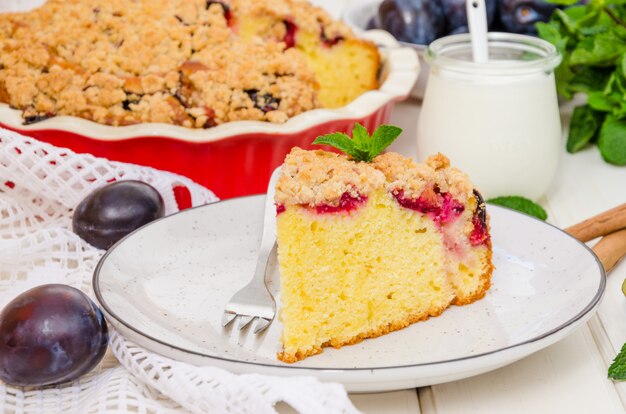 Torte mit Pflaumen und shtreisel auf einer Platte auf einer weißen Holzoberfläche