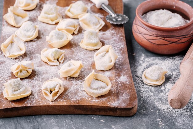 Tortellini casero crudo fresco o pasta de ravioli sobre fondo oscuro