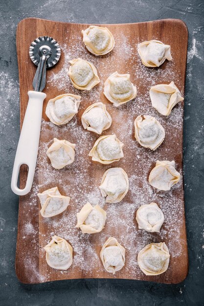 Tortellini casero crudo fresco o pasta de ravioli sobre fondo oscuro