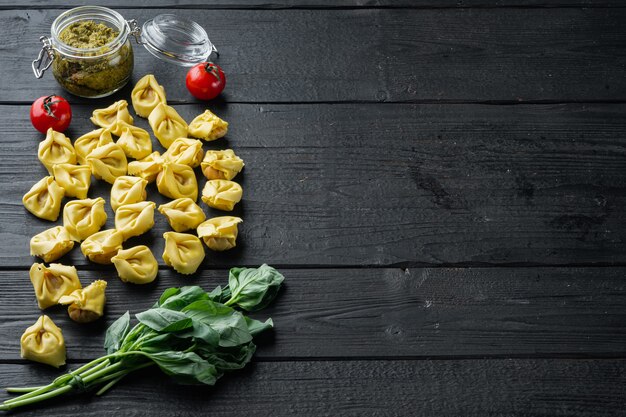 Tortellini cru com manjericão e pesto de pinho, na mesa de madeira preta