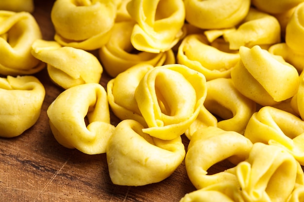 Tortellini crudo sobre la plancha de madera, preparado para cocinar