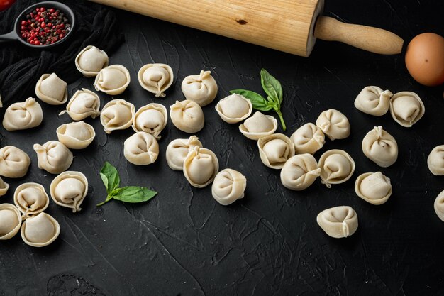 Tortellini mit Parmesan und Basilikum, auf schwarzem Hintergrund