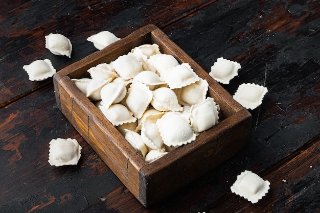 Tortellini y ravioles de bolas de masa congeladas en caja de madera en la vieja mesa de madera oscura.