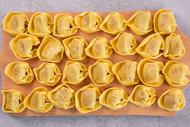 Tortelloni crudo con relleno de champiñones sobre una tabla de madera