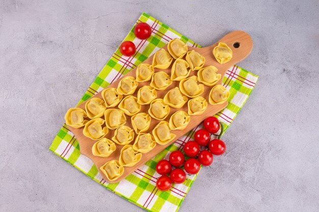 Tortelloni crudo con relleno de champiñones sobre una tabla de madera