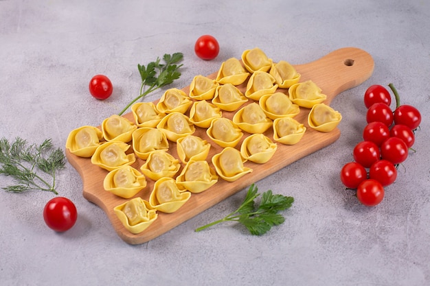 Tortelloni crudo con relleno de champiñones sobre una tabla de madera