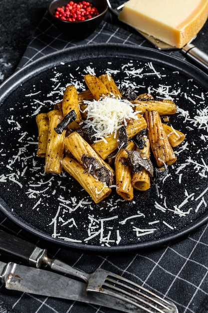 Tortiglioni de pasta con trufa negra y Boletus edulis, seta blanca. Fondo negro. Vista superior