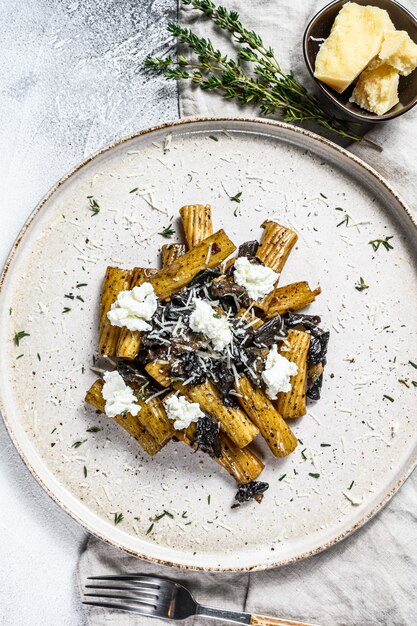 Tortiglioni de pasta con trufa negra, champiñones blancos, salsa de crema y queso ricotta. Fondo gris Vista superior