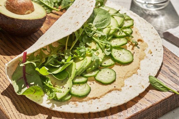 Tortilha vegetariana com homus e vegetais verdes