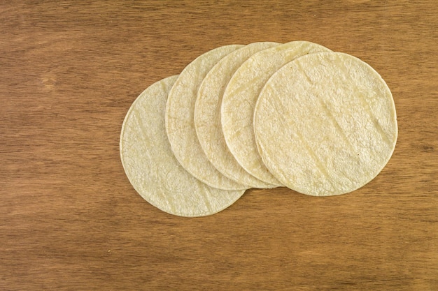 Tortilhas de milho branco em uma mesa de madeira.