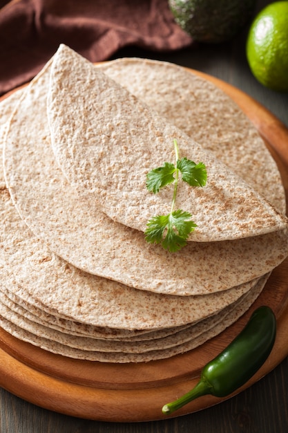 Tortilhas de trigo integral na placa de madeira e legumes