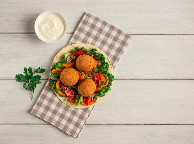 Tortilhas embrulhadas bolas de falafel com legumes frescos, comida saudável vegetariana em um fundo branco de madeira sem foco seletivo de pessoas