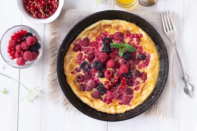 Foto tortilla con bayas en sartén sobre mesa de madera