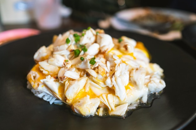 Tortilla de cangrejo sobre arroz La tortilla esponjosa con trozos de carne fresca de cangrejo se coloca sobre un montículo de arroz al vapor y se cubre con rodajas de cebollín Menú con influencia china en el restaurante de Bangkok