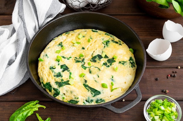 Tortilla de cebolletas con espinacas y queso feta en una sartén de hierro fundido