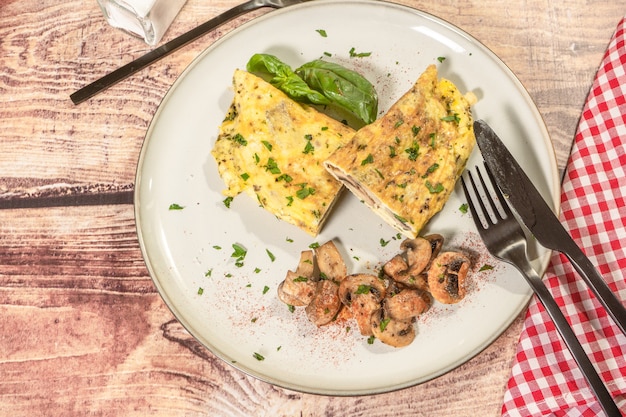 Tortilla de champiñones cortada por la mitad y servida en un plato con unos champiñones salteados como guarnición