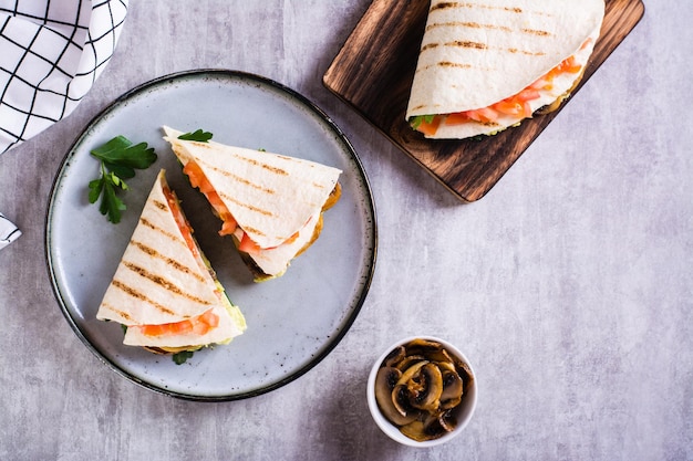 Tortilla con champiñones fritos con guacamole, tomates y hierbas en una vista superior del plato