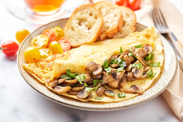 Tortilla con champiñones y perejil en placa sobre fondo de mármol. Frittata - tortilla italiana para el desayuno o el almuerzo.