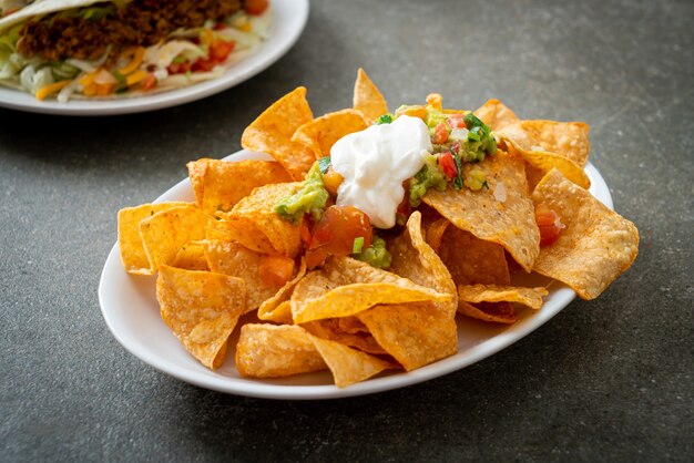 Tortilla chips de nachos mexicanos con jalapeño, guacamole, salsa de tomates y dip