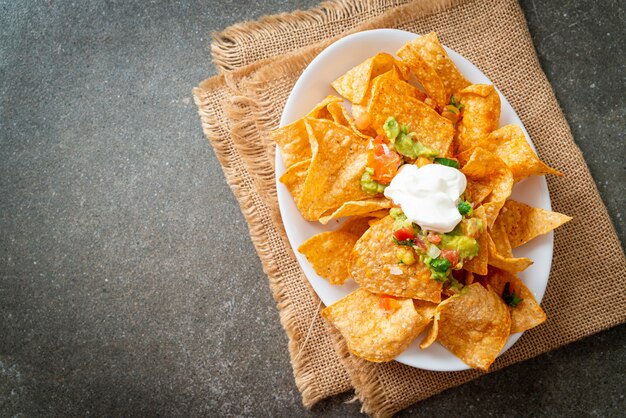 Tortilla chips de nachos mexicanos con jalapeño, guacamole, salsa de tomates y dip