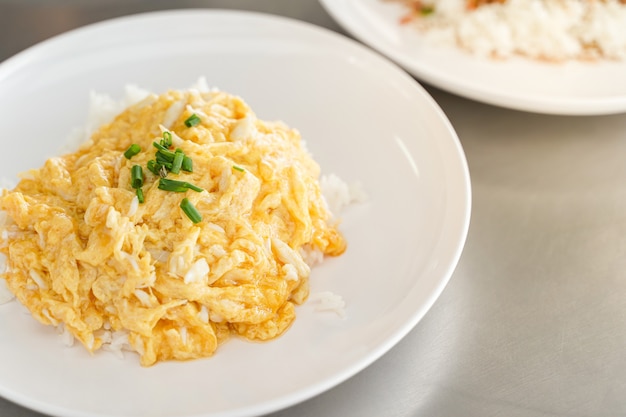 Tortilla cremosa con carne de cangrejo sobre arroz en plato blanco.