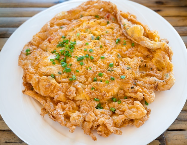 Tortilla crujiente con hojas de cebolla verde en rodajas en la placa blanca.