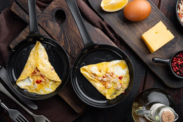 Tortilla de desayuno frito con carne de cangrejo y queso, en una sartén de hierro, sobre fondo de madera oscura, vista superior plana