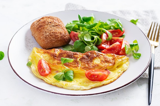 Tortilla con ensalada de tomate, jamón, queso y maíz en un plato. Frittata - tortilla italiana.