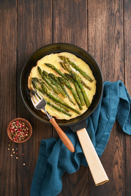 Tortilla con espárragos Frittata o revueltos con espárragos en sartén con perejil y pimienta sobre fondo de mesa de madera vieja Concepto de desayuno útil Vista superior