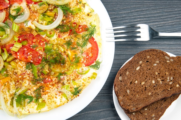 Tortilla frita cocida con hierbas y verduras en un plato blanco sobre una mesa de madera